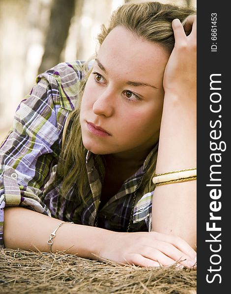 Young laying pensive woman over dead pine tree leaves. Young laying pensive woman over dead pine tree leaves.