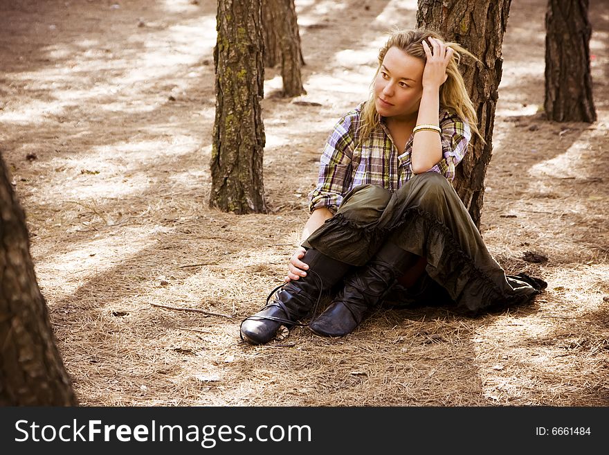 Young blond woman sitting in autumn forest. Young blond woman sitting in autumn forest.