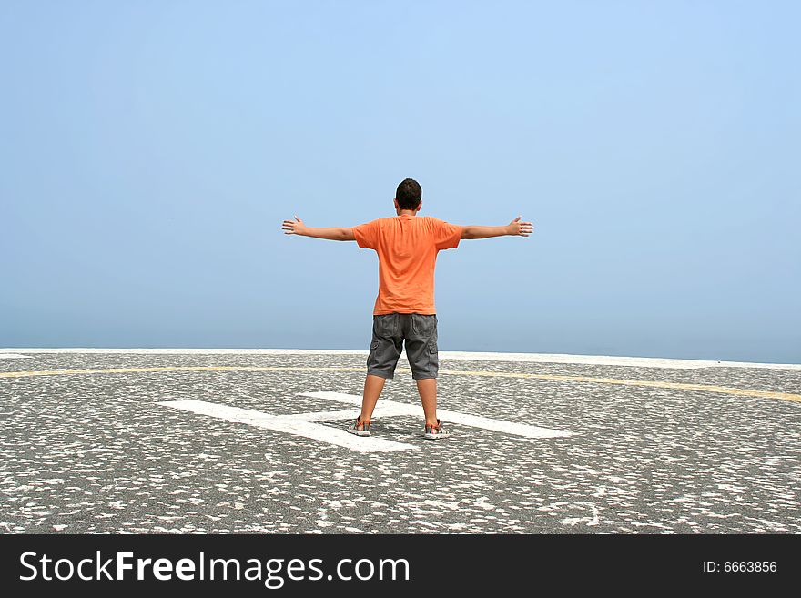 Boy with arms wide open contemplating the ocean in foggy day. Boy with arms wide open contemplating the ocean in foggy day