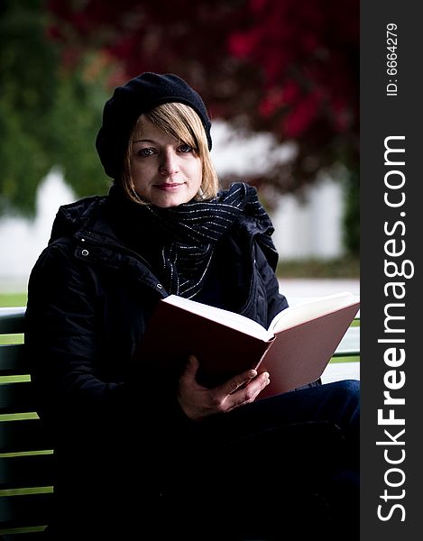 Girl reading a book outside on a park bench. Girl reading a book outside on a park bench