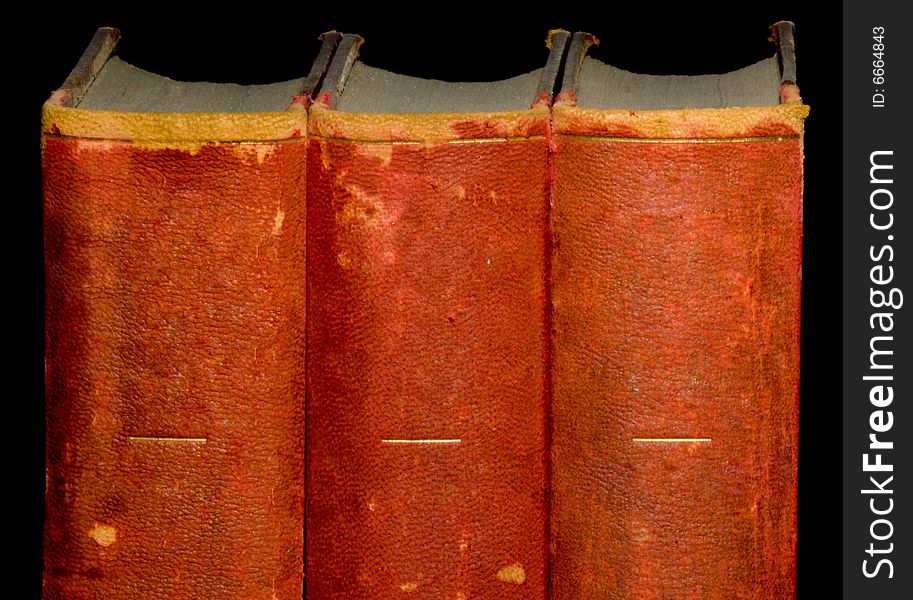A row of old leather bound books isolated on a black background