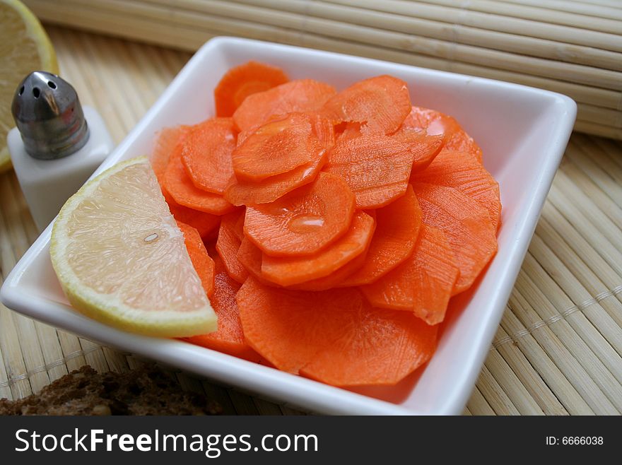 A fresh salad of carrots with a piece of lemon