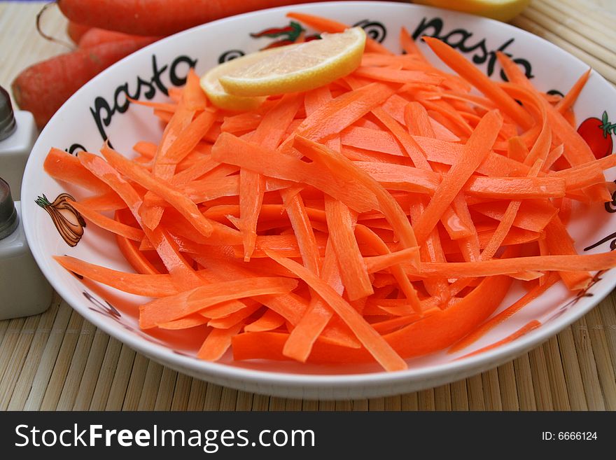 A fresh salad of carrots with a piece of lemon