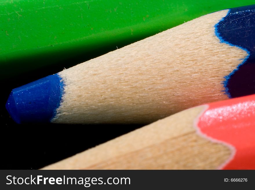 Closeup of three coloured pencils in red, blue and green. Black background. Closeup of three coloured pencils in red, blue and green. Black background.