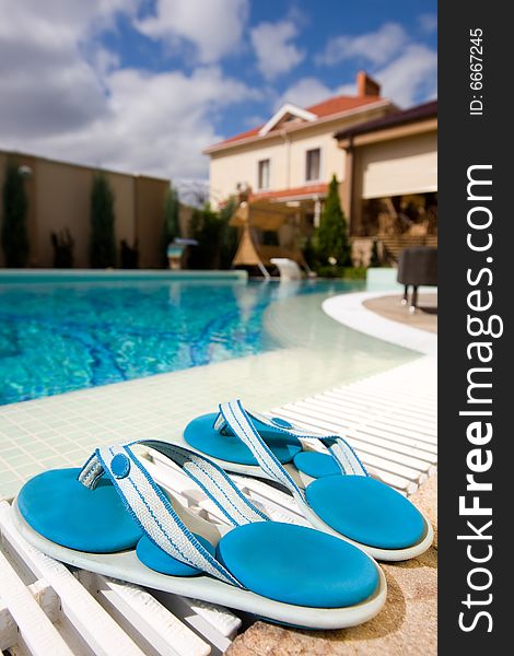 Two blue slippers near swimming pool in hotel