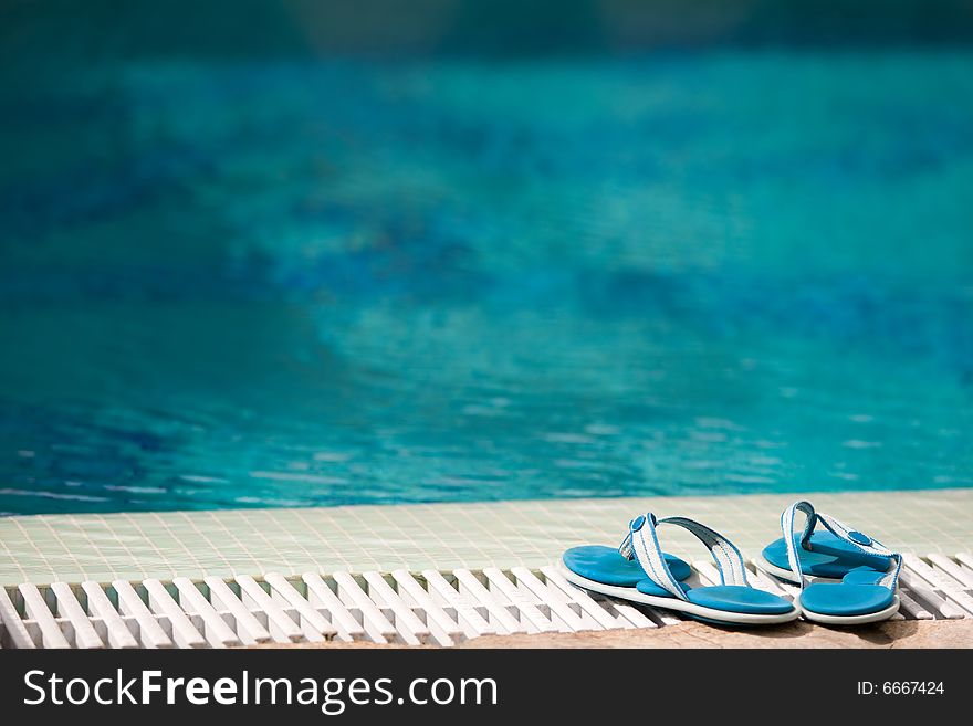 Two blue slippers near swimming pool in hotel