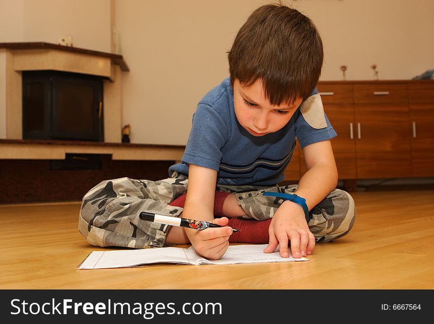 Little boy learning to writeon a floor