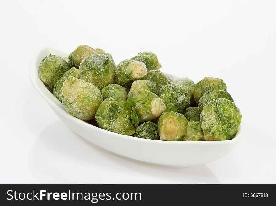 Frozen Brussels sprouts in a bowl on bright background
