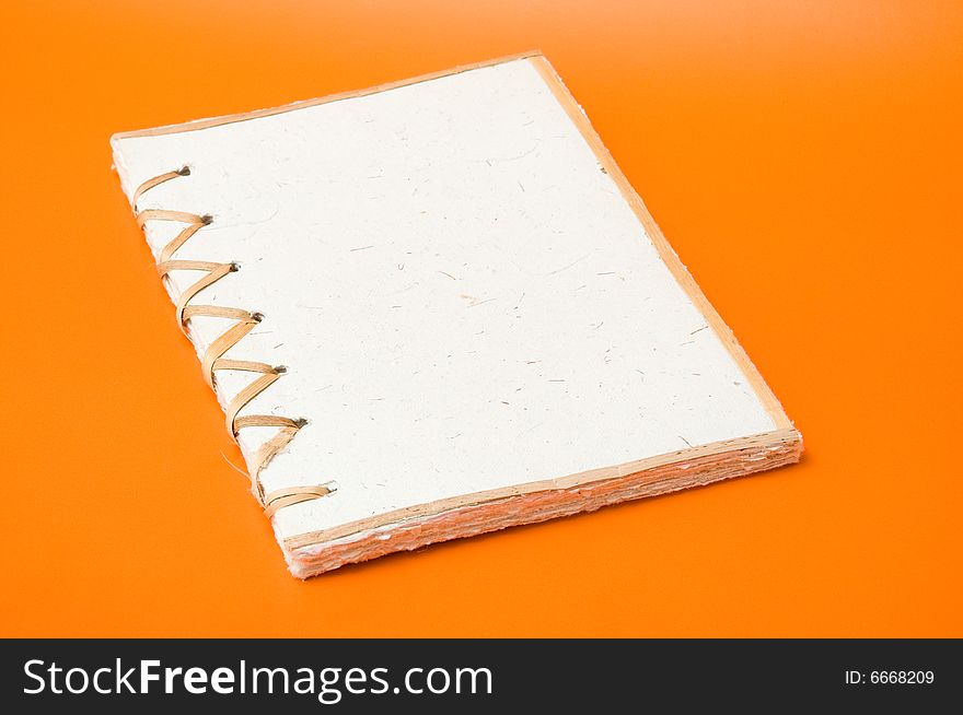 Recycled notepad over an orange background. Recycled notepad over an orange background