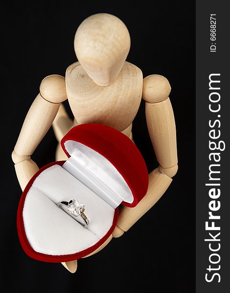 A beautiful crystal white engagement ring in a red juwelery box , held by a wooden mannequin. A beautiful crystal white engagement ring in a red juwelery box , held by a wooden mannequin