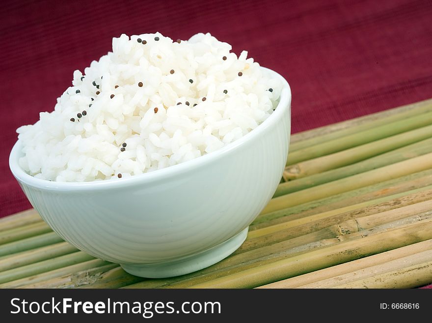 White bowl of boil chinese rice over bamboo