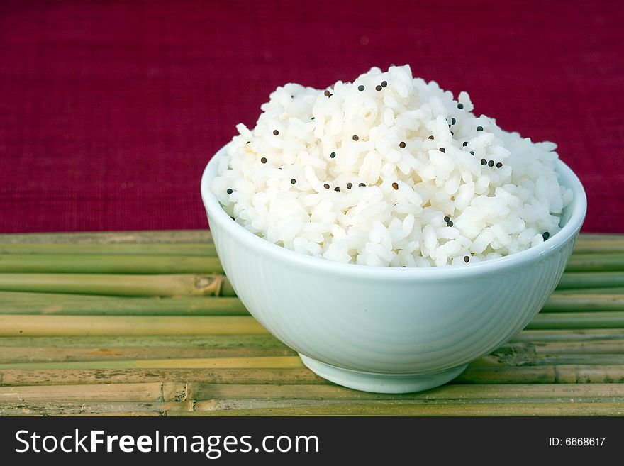 White bowl of boil chinese rice  over bamboo