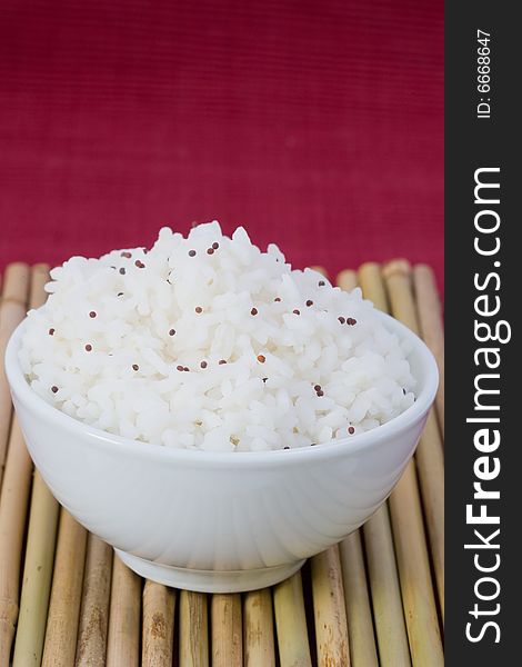 White bowl of boil chinese rice over bamboo