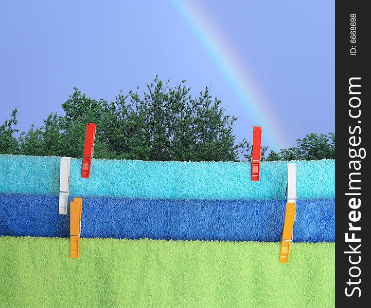 Towels hanging with rope and clothespins on background with rainbow