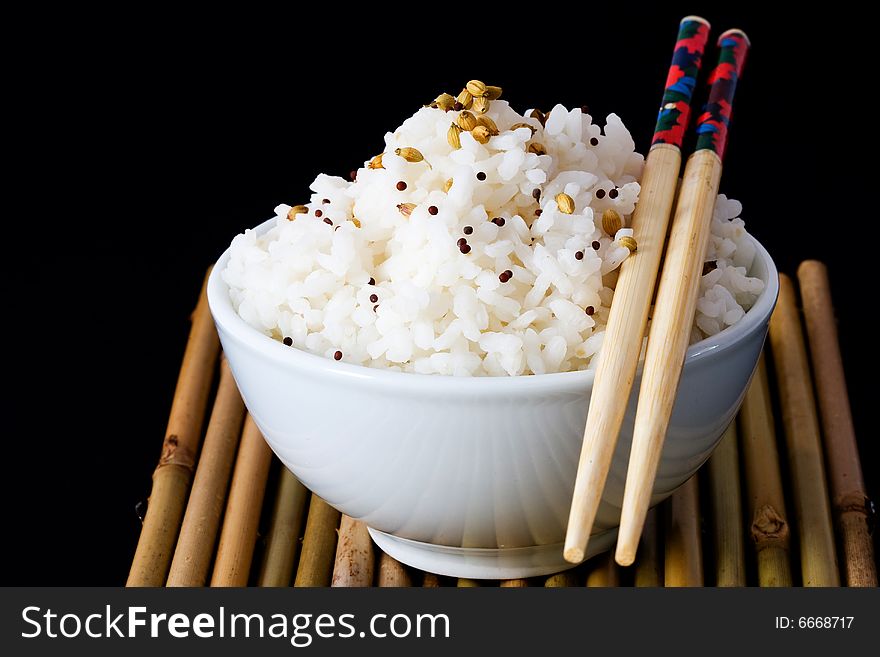 White bowl of boil chinese rice over bamboo