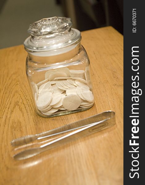 Communion wafers sitting on a wooden table with silver tongs