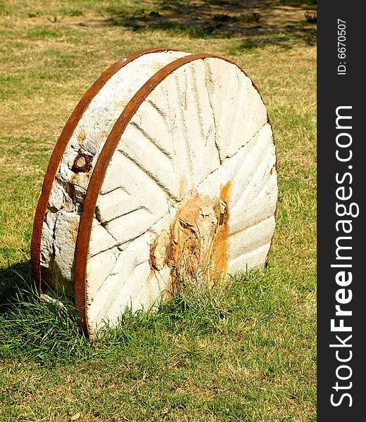 A beautiful close up of an old millstone buried in a field. A beautiful close up of an old millstone buried in a field