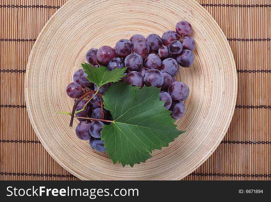 Cluster of grapes on wooden plate - close up. Cluster of grapes on wooden plate - close up