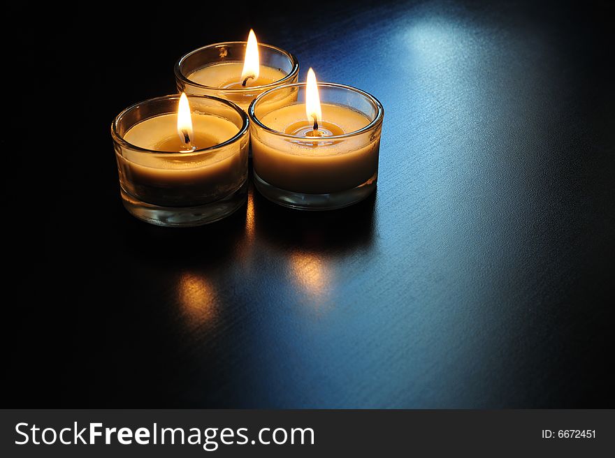 Close up of three burning candles on a black table