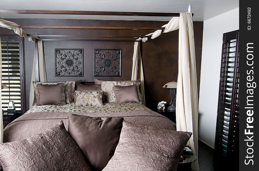 Beautifully decorated bedroom with dark wood florring shutters and four poster bed