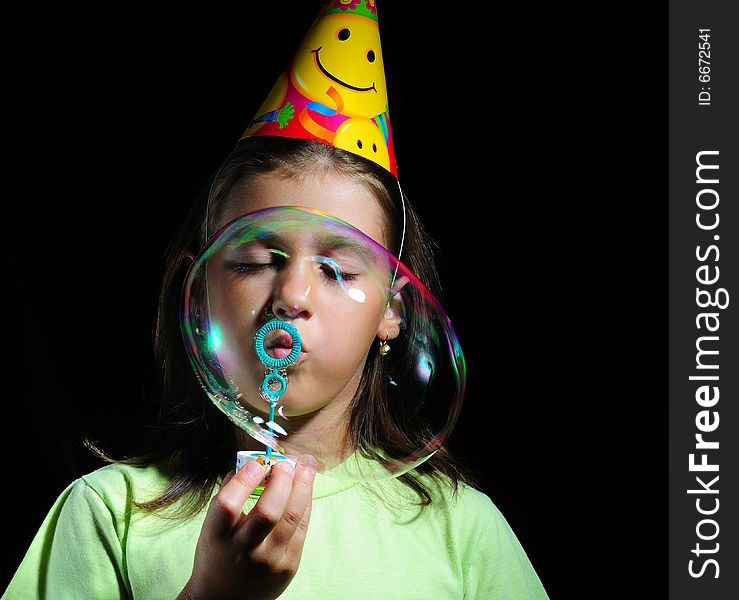 Little girl blowing soap bubbles, children's birthday party