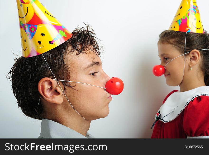 A little girl and a boy with party horn and clown noses