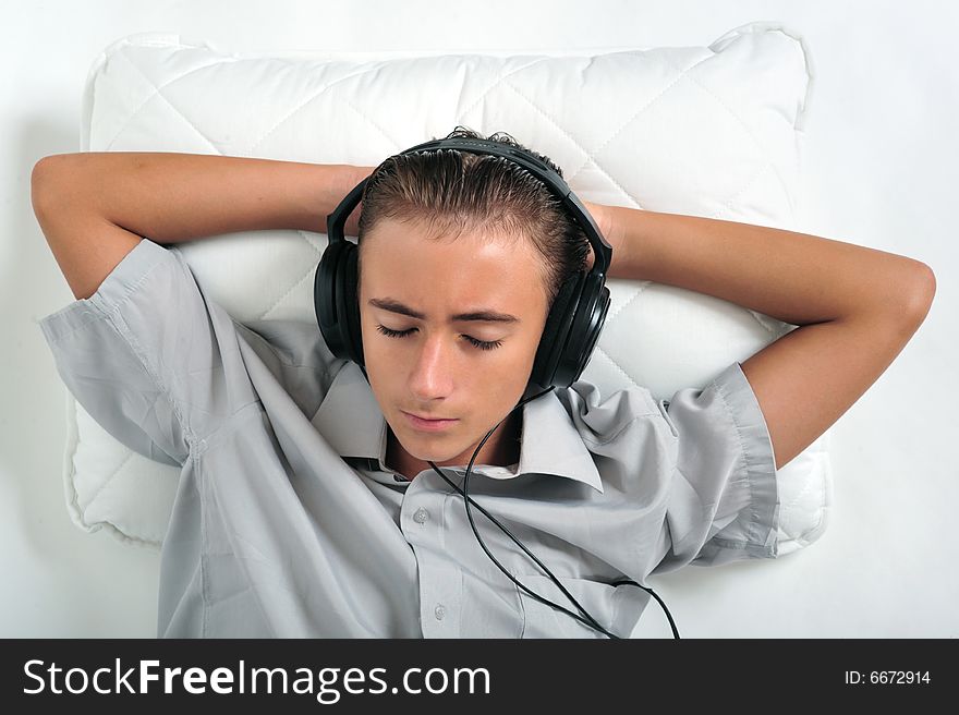 Young boy relaxing on pillow with headphones on ears