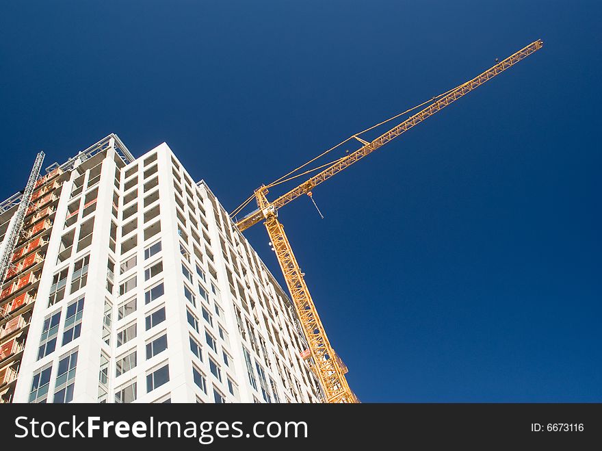 Yellow Crane Over White Skyscraper