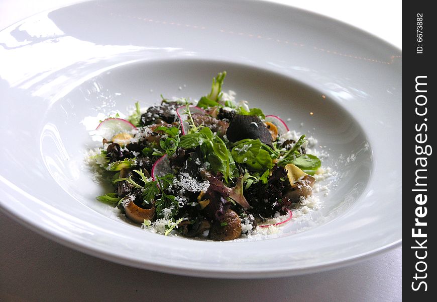 A dish which is contains mushroom, salad and black truffle. A dish which is contains mushroom, salad and black truffle.