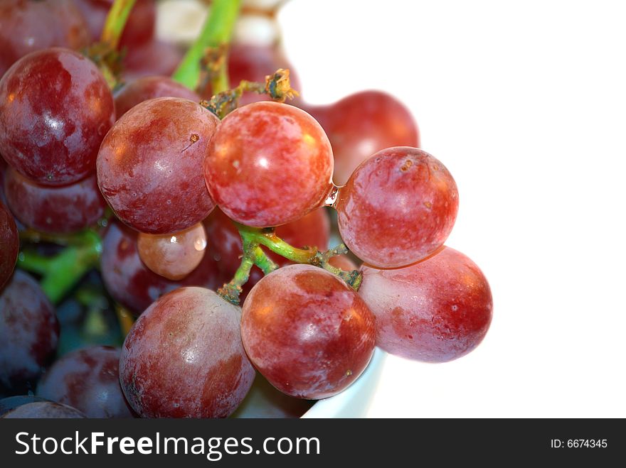 Fresh juicy red grapes berry hang down from white bowl. Fresh juicy red grapes berry hang down from white bowl.
