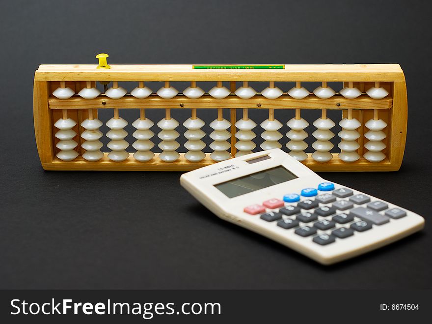 A traditional abacus and a modern calculator on black background. A traditional abacus and a modern calculator on black background
