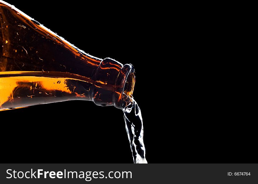 Flowing water from bottle isolated on black