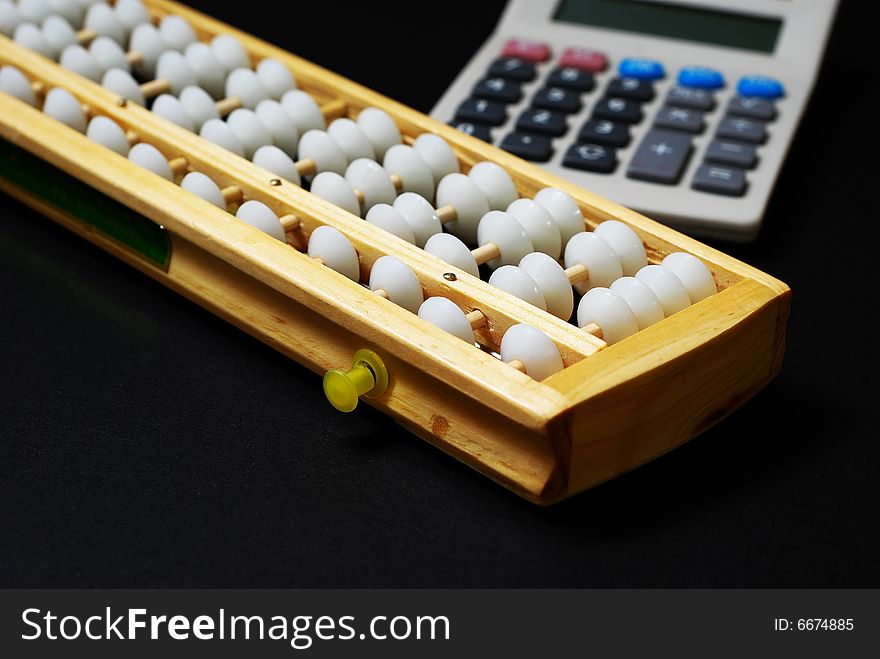 A traditional abacus and a modern calculator on black background. A traditional abacus and a modern calculator on black background