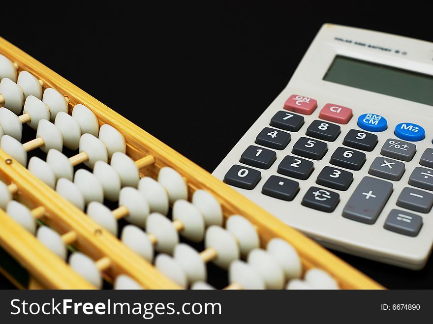 A traditional abacus and a modern calculator on black background. A traditional abacus and a modern calculator on black background