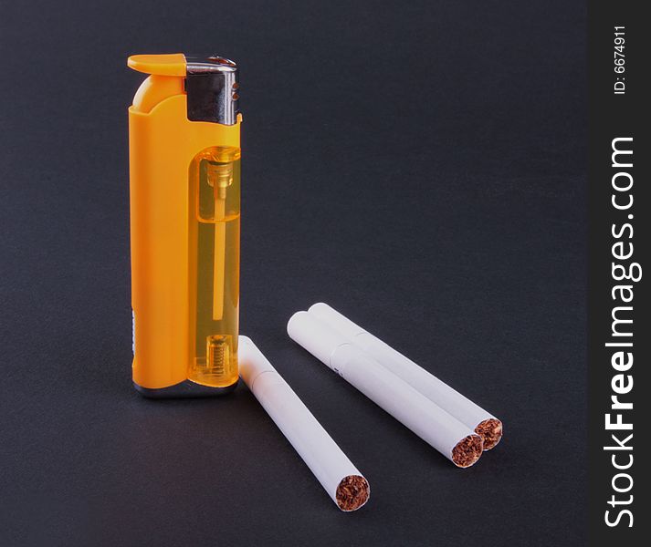 Cigarette-lighter and cigarettes isolated on dark background