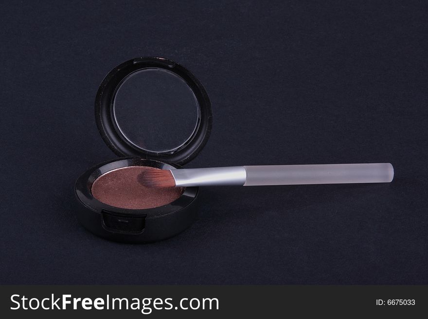 Eyeshadow and brush isolated on dark background