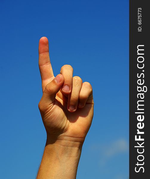Hand pointing with index finger against a sky background