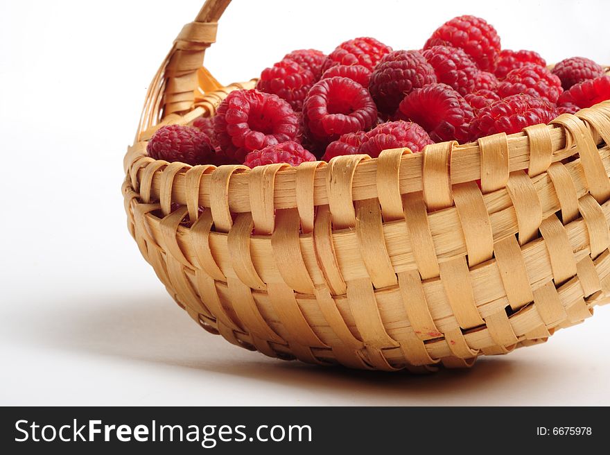 Red raspberry on white background, focus on basket