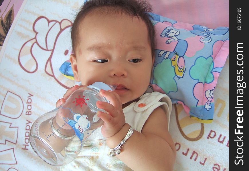 A baby is drinking water with baby's bottle. A baby is drinking water with baby's bottle