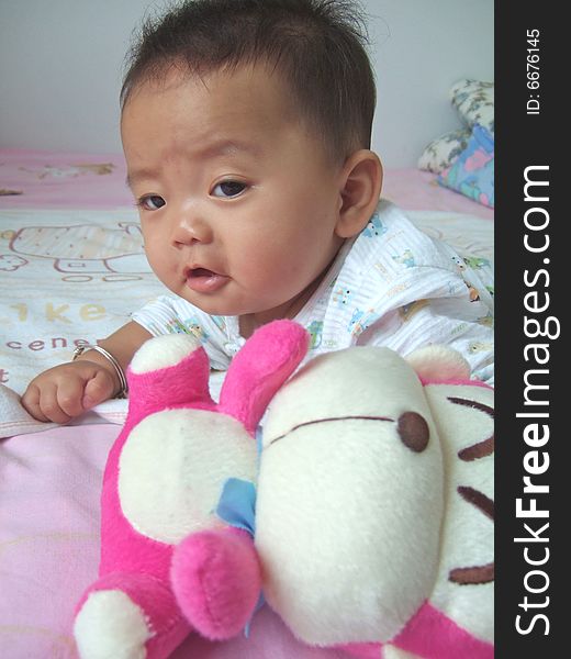 Lovely baby and toy monkey on a bed