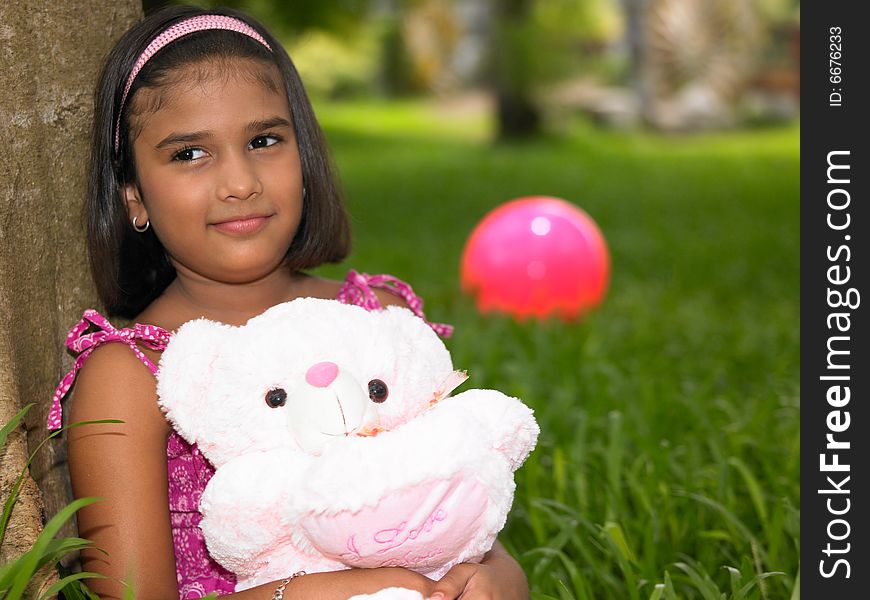 Asian girl in a garden with her teddy bear