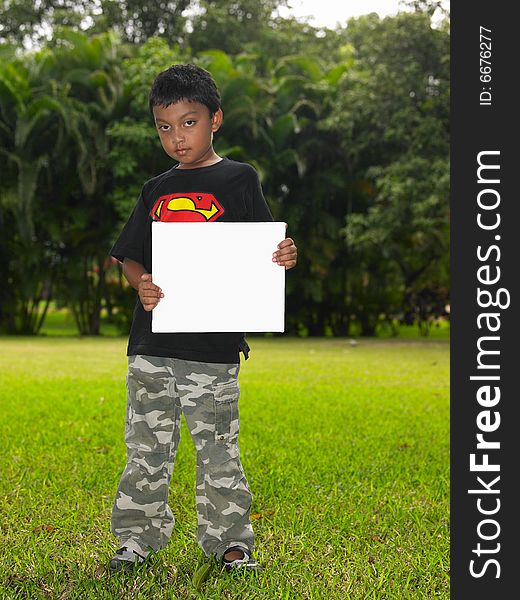 Asian boy of indian origin holding a placard in a park. Asian boy of indian origin holding a placard in a park