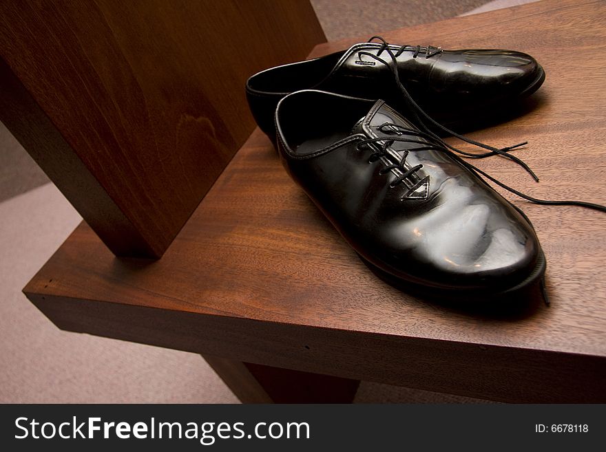 Dress shoes sitting on a dark wooden bench at a church. Dress shoes sitting on a dark wooden bench at a church