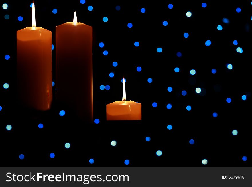 Three large candles lit amongst blue lights