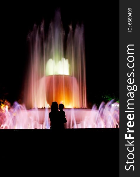 Silhouette of mother and baby over colorful fountain background. Silhouette of mother and baby over colorful fountain background