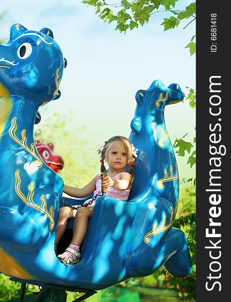 Little girl goes for a drive on roundabouts in children's park