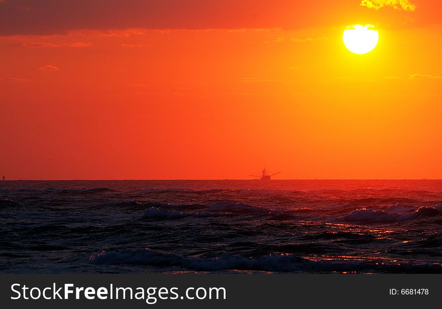 Sunrise on East coast of USA. Visible in image is a fishing trawler with outriggers deployed on the horizon. Sunrise on East coast of USA. Visible in image is a fishing trawler with outriggers deployed on the horizon.