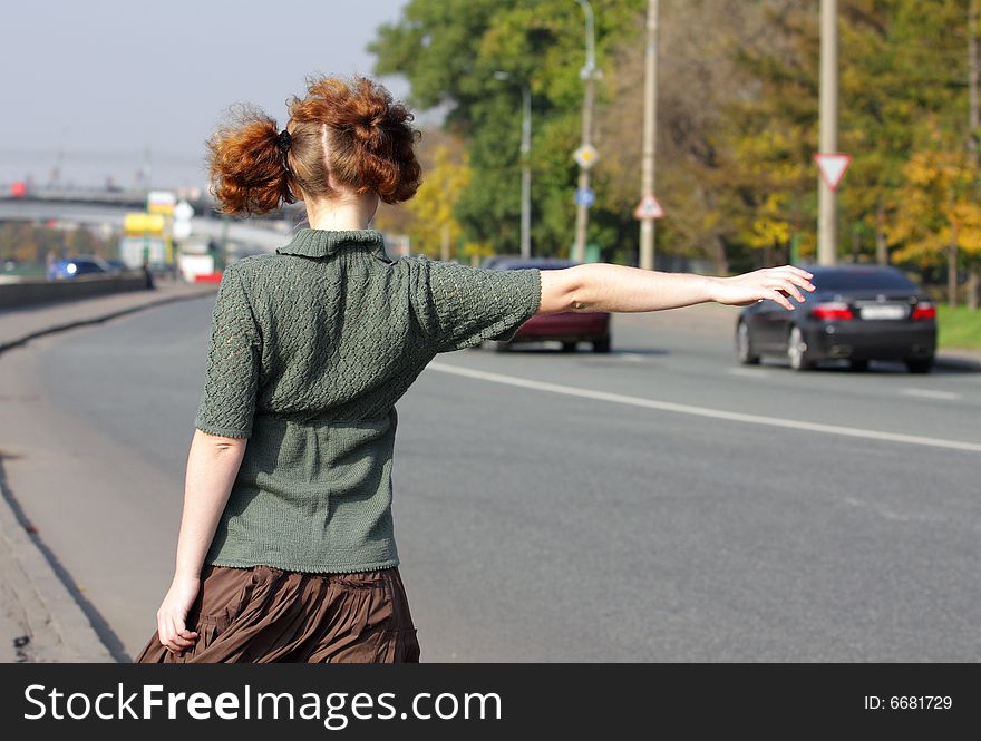 Girl is hitch-hiking on road in summer day