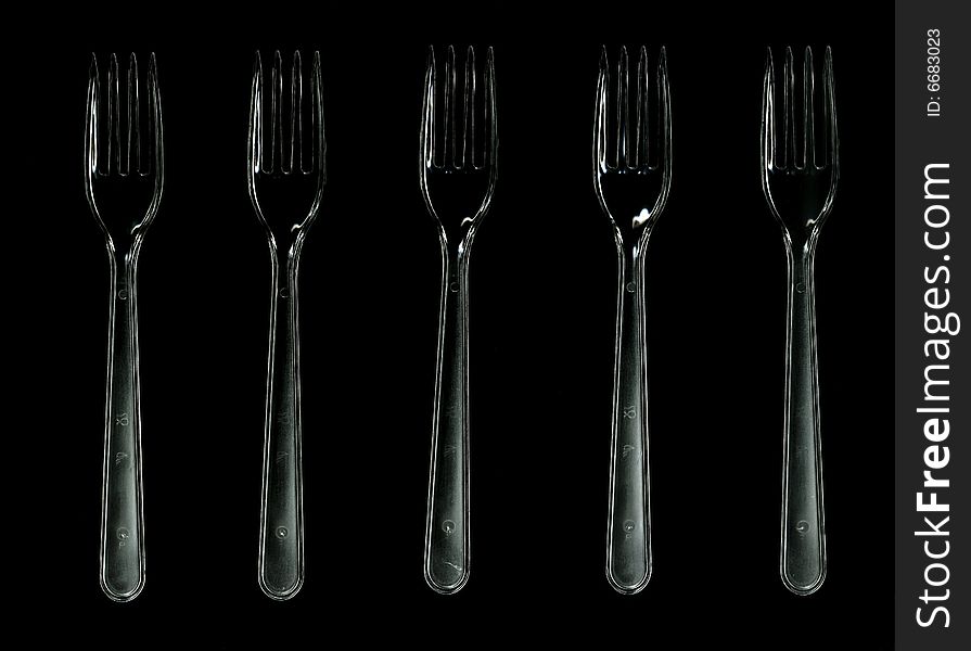 Five transparent plastic forks isolated on black