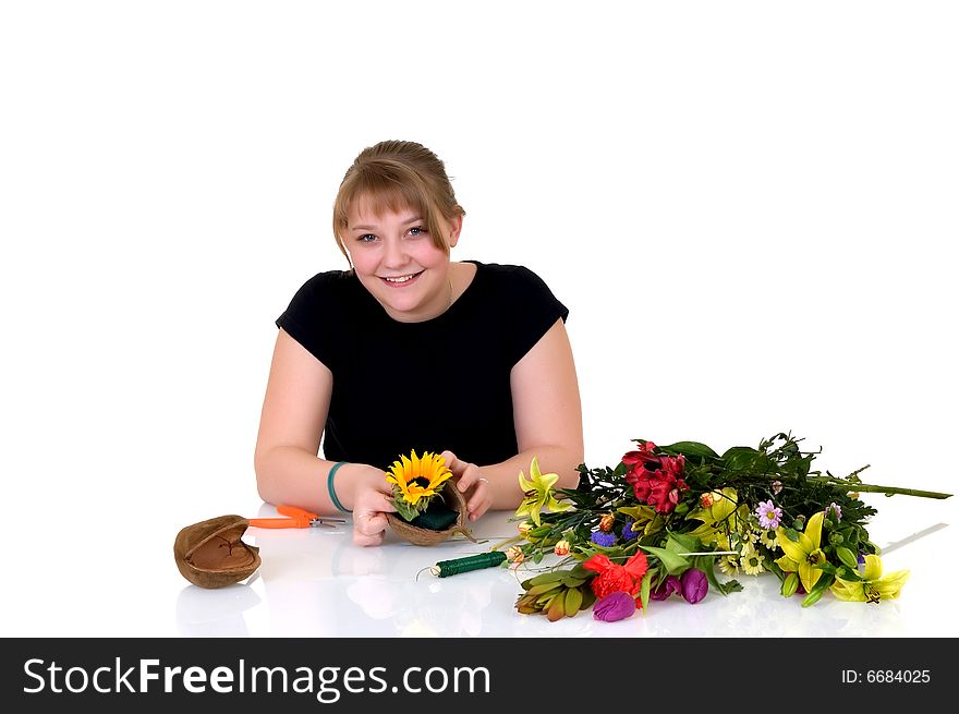 Young girl arranging flowers on reflective surface, white background, studio shot